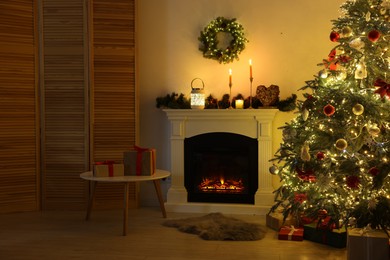 Decorated Christmas tree near fireplace in room. Festive interior design