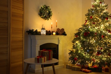 Photo of Decorated Christmas tree near fireplace in room. Festive interior design