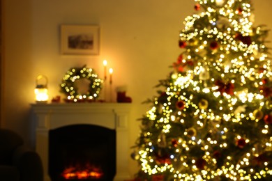 Blurred view of decorated Christmas tree near fireplace in room. Festive interior design