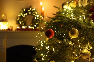 Photo of Decorated Christmas tree near fireplace in room, closeup. Festive interior design