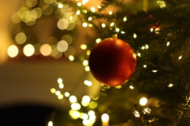 Photo of Christmas tree decorated with bauble and festive lights indoors, closeup. Bokeh effect