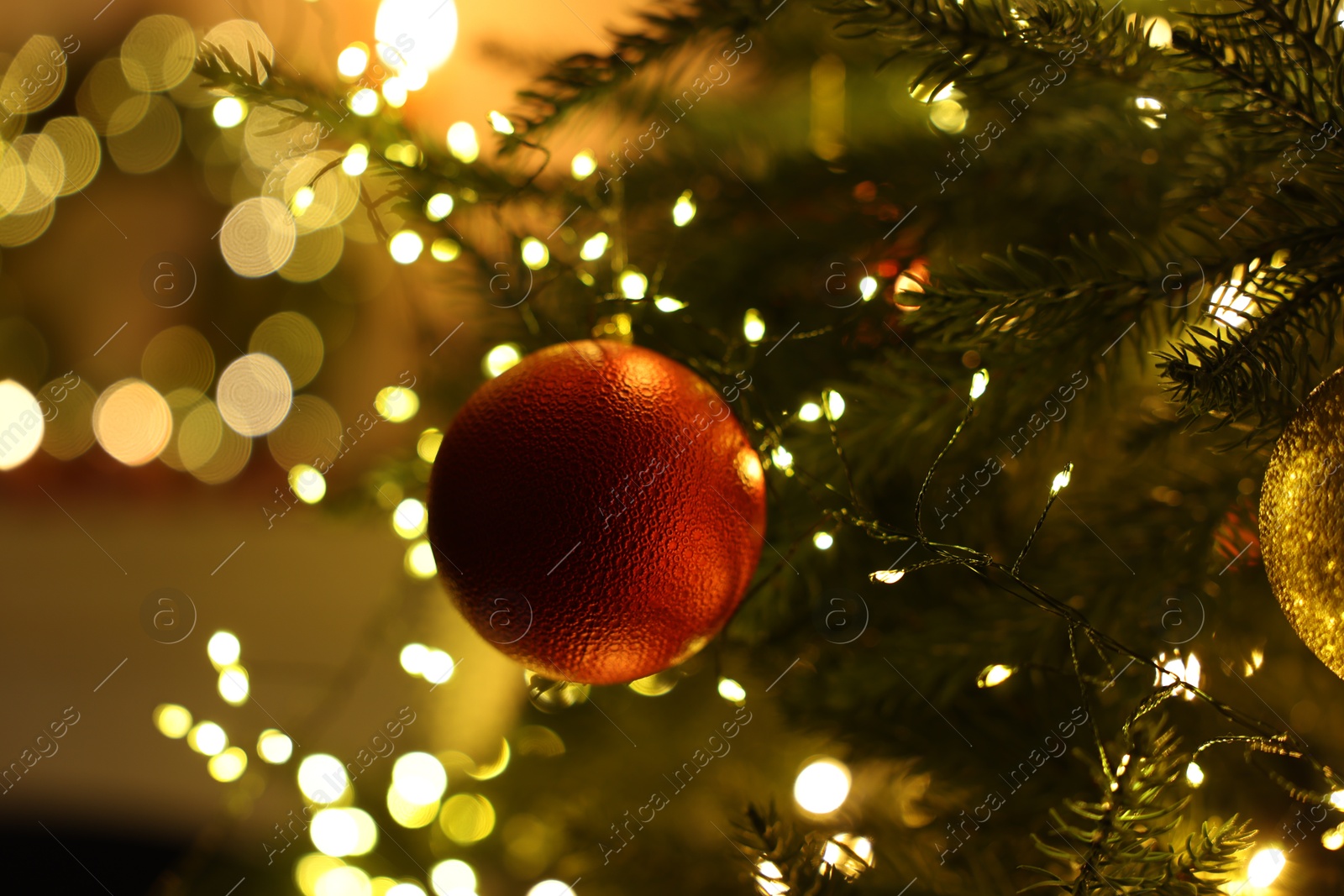 Photo of Christmas tree decorated with bauble and festive lights indoors, closeup. Bokeh effect