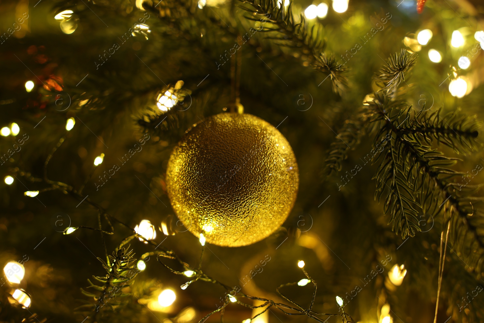 Photo of Christmas tree decorated with bauble and festive lights indoors, closeup