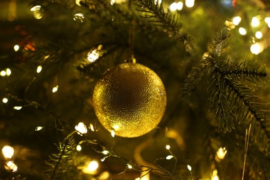 Christmas tree decorated with bauble and festive lights indoors, closeup