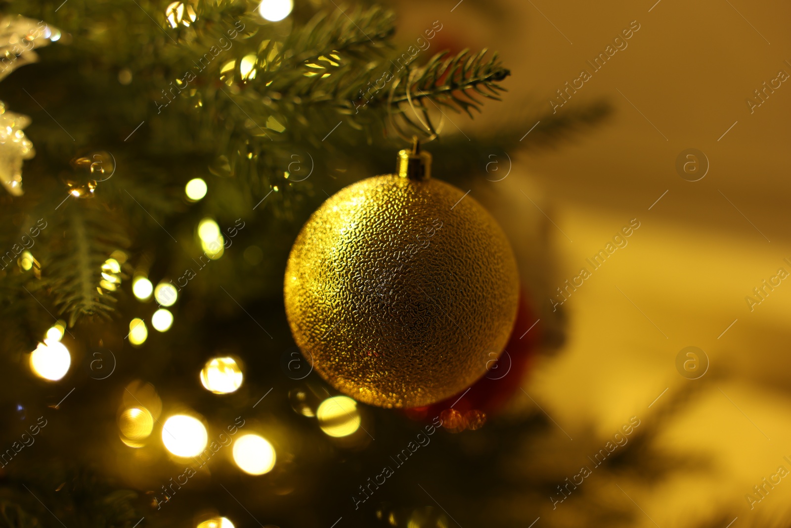 Photo of Christmas tree decorated with bauble and festive lights indoors, closeup