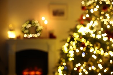 Blurred view of decorated Christmas tree near fireplace in room. Festive interior design