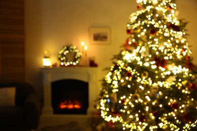 Blurred view of decorated Christmas tree near fireplace in room. Festive interior design