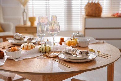 Stylish table setting with beautiful dishware and autumn decor in dining room