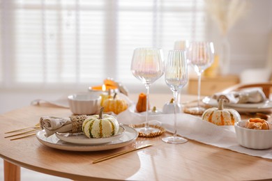 Stylish table setting with beautiful dishware and autumn decor in dining room