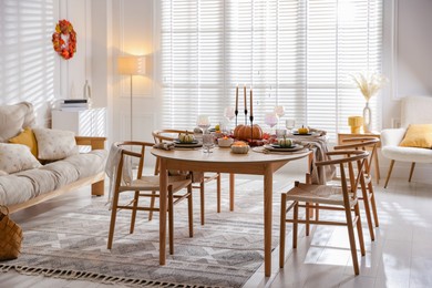 Photo of Stylish table setting with beautiful dishware and autumn decor in dining room