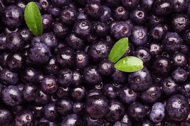 Photo of Wet acai berries and leaves as background, top view