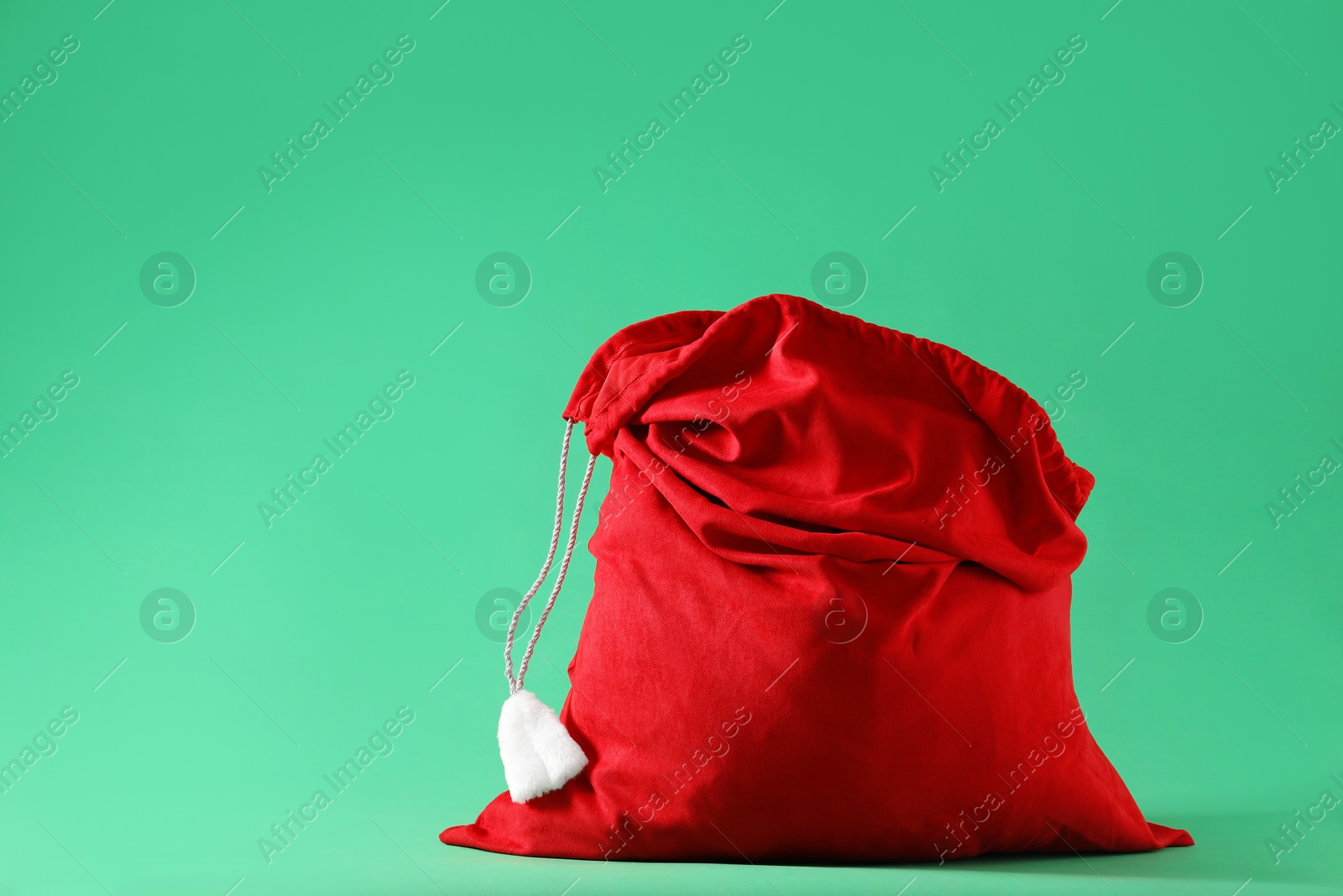 Photo of Red Santa Claus bag on green background, space for text