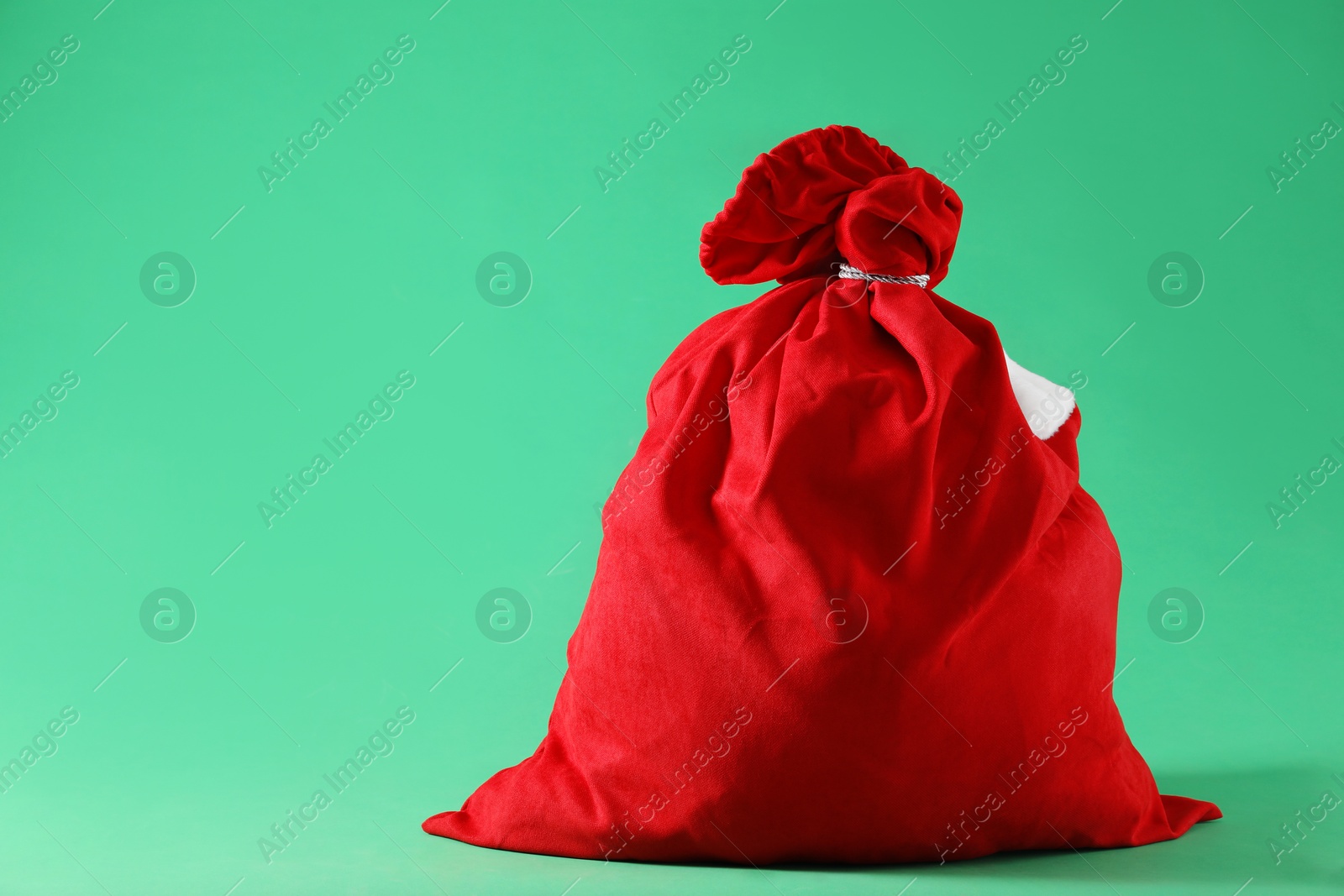 Photo of Red Santa Claus bag on green background, space for text