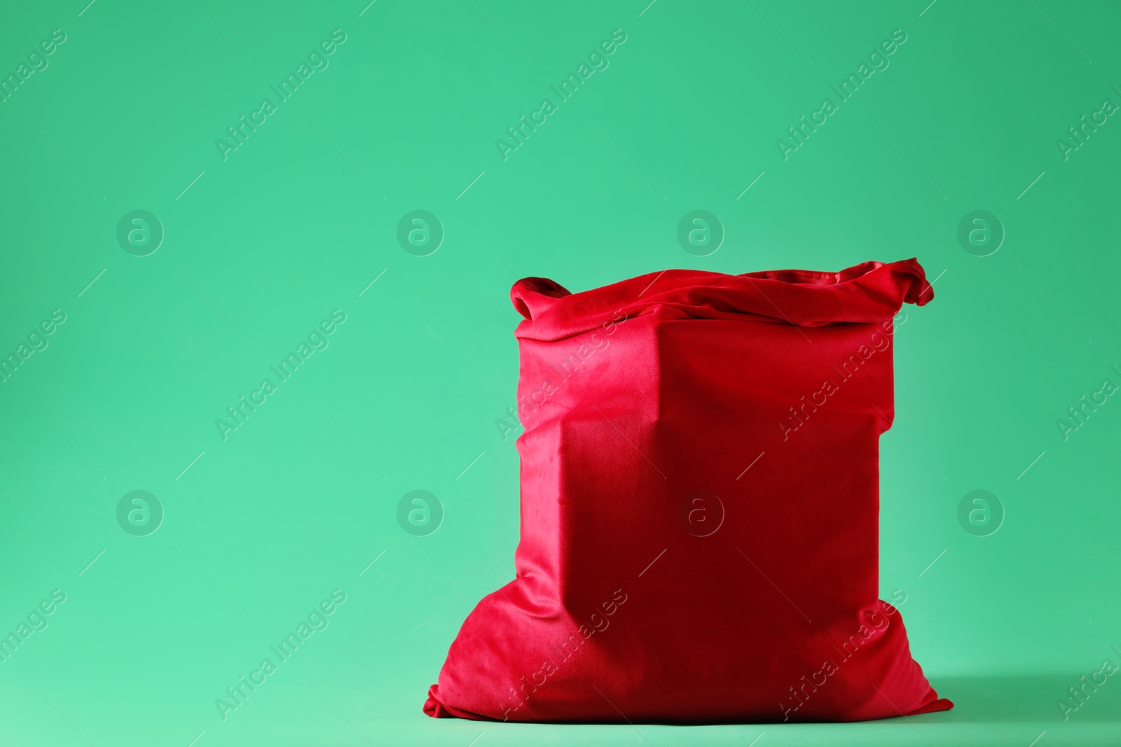 Photo of Red Santa Claus bag on green background, space for text