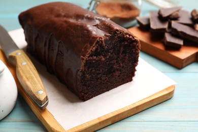 Photo of Tasty chocolate sponge cake on light blue wooden table, closeup