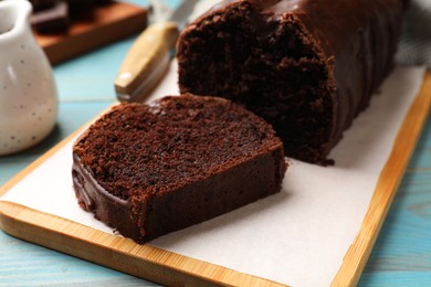 Photo of Tasty chocolate sponge cake on light blue wooden table, closeup