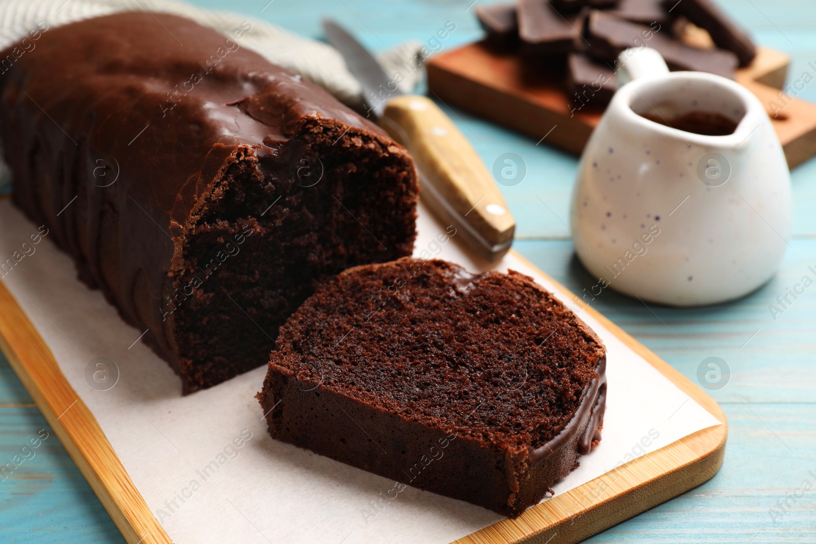 Photo of Tasty chocolate sponge cake on light blue wooden table, closeup