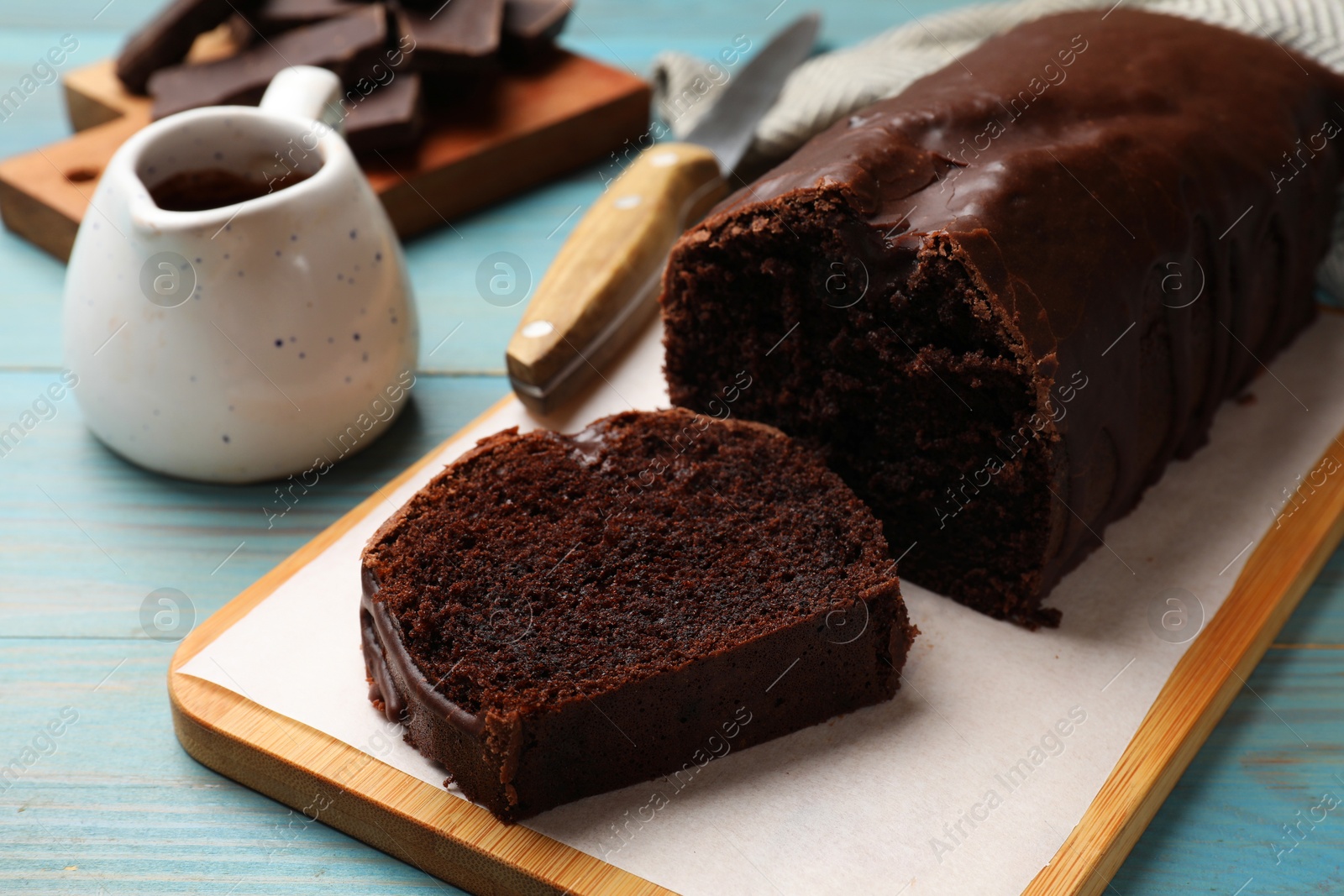 Photo of Tasty chocolate sponge cake on light blue wooden table, closeup