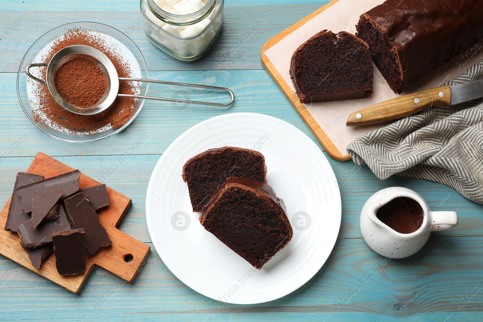 Photo of Tasty chocolate sponge cake and ingredients on light blue wooden table, top view