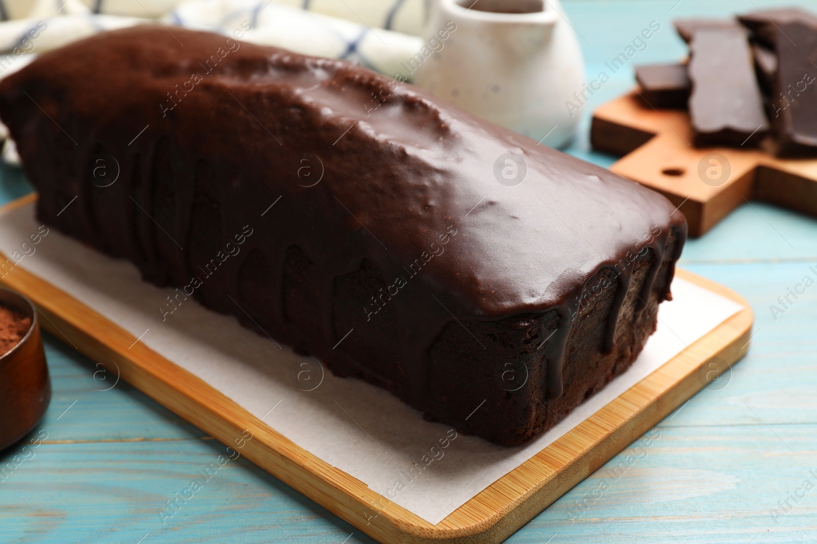 Photo of Tasty chocolate sponge cake on light blue wooden table, closeup