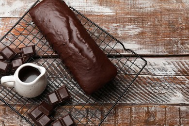 Tasty sponge cake and pieces of chocolate on wooden table, top view