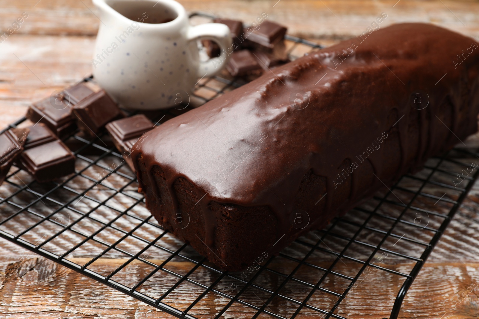 Photo of Tasty sponge cake and pieces of chocolate on wooden table, closeup