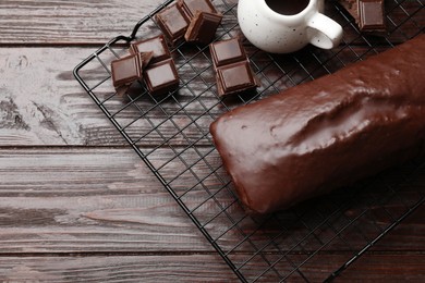 Photo of Tasty sponge cake and pieces of chocolate on wooden table, top view