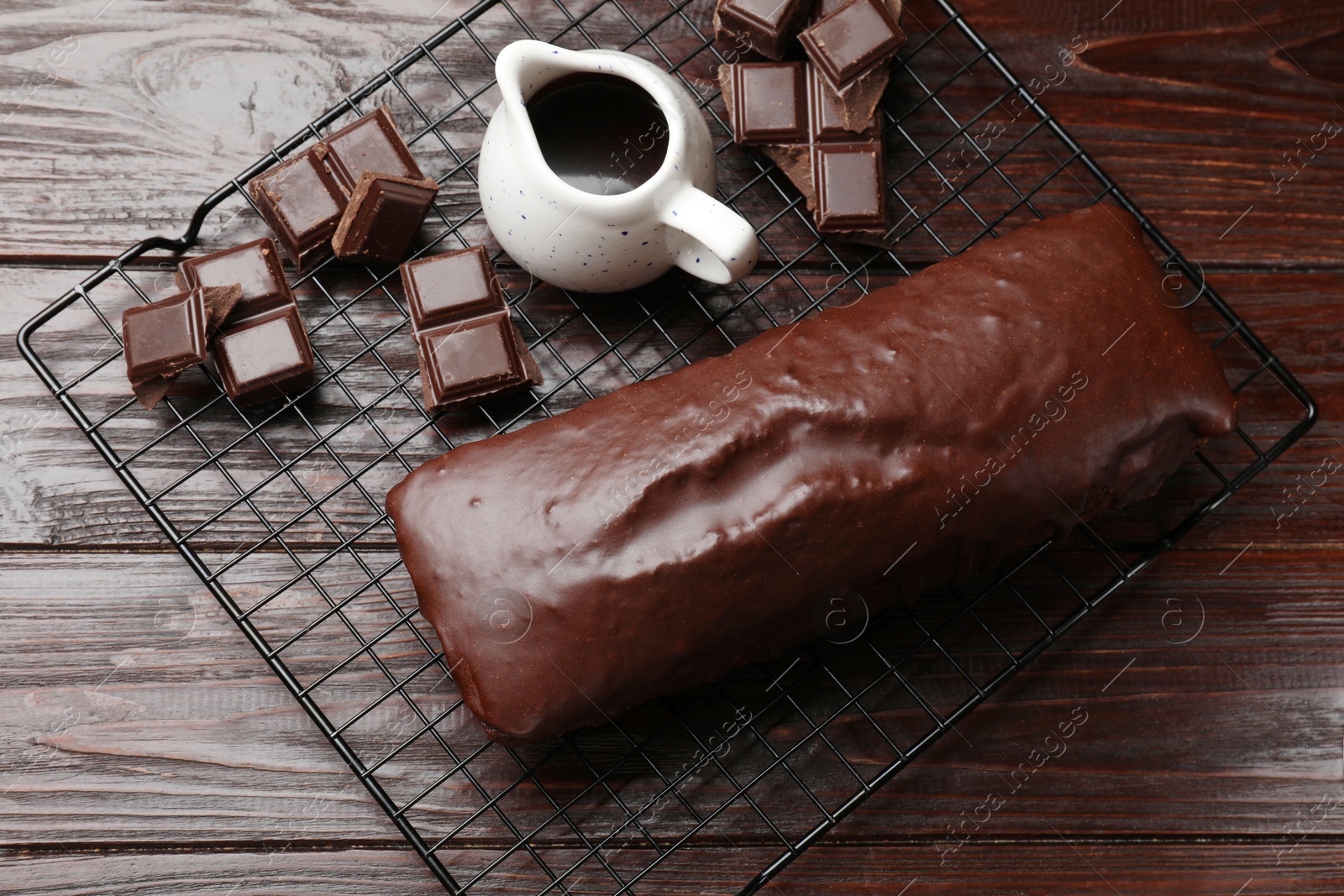 Photo of Tasty sponge cake and pieces of chocolate on wooden table, top view