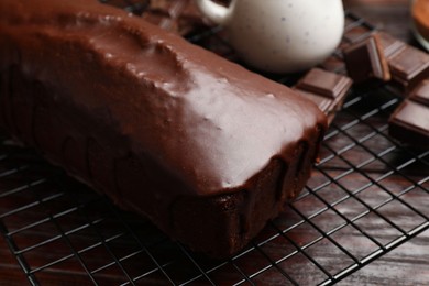 Photo of Tasty sponge cake and pieces of chocolate on wooden table, closeup