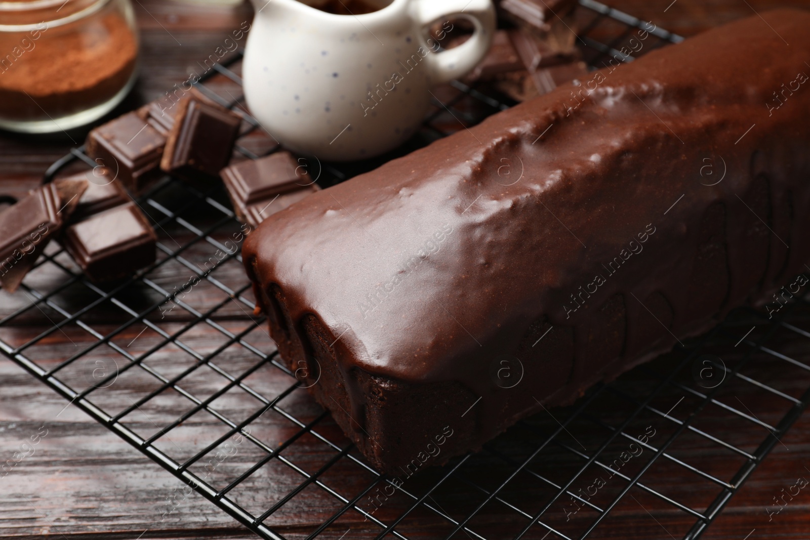 Photo of Tasty sponge cake and pieces of chocolate on wooden table, closeup