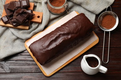 Photo of Tasty chocolate sponge cake and ingredients on wooden table, top view