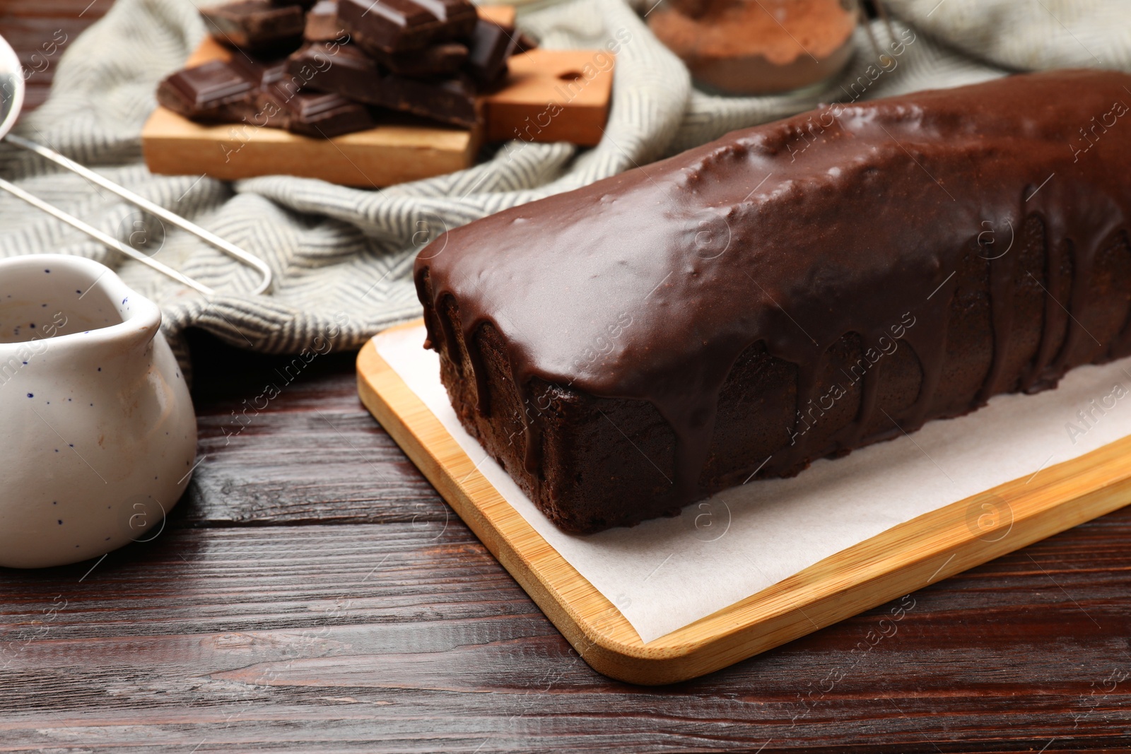 Photo of Tasty sponge cake and pieces of chocolate on wooden table, closeup