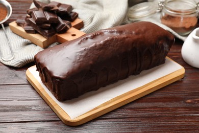 Photo of Tasty sponge cake and pieces of chocolate on wooden table, closeup