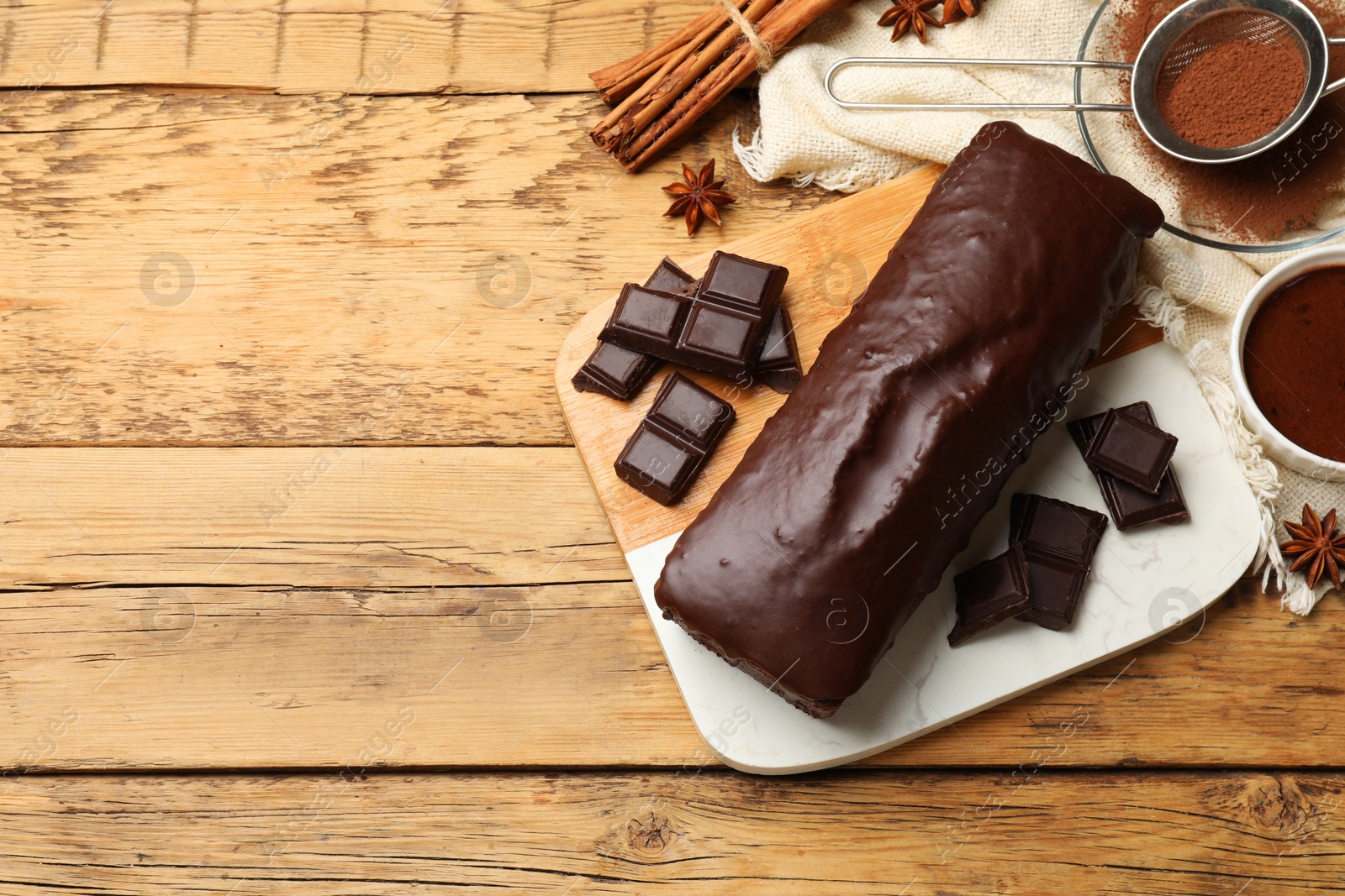 Photo of Tasty chocolate sponge cake and ingredients on wooden table, top view. Space for text