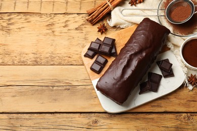 Photo of Tasty chocolate sponge cake and ingredients on wooden table, top view. Space for text