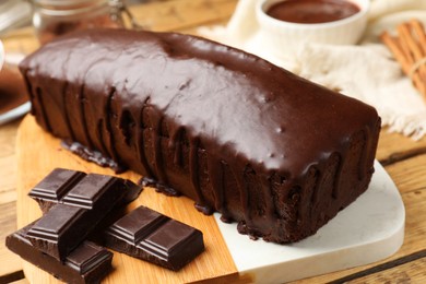 Photo of Tasty sponge cake and pieces of chocolate on wooden table, closeup