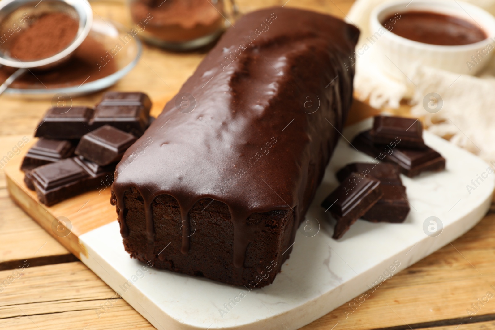 Photo of Tasty sponge cake and pieces of chocolate on wooden table, closeup