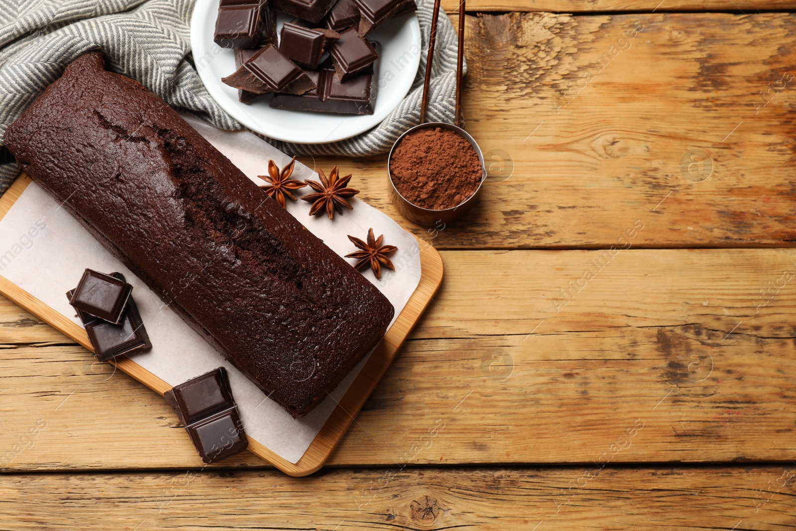 Photo of Tasty chocolate sponge cake and ingredients on wooden table, top view. Space for text