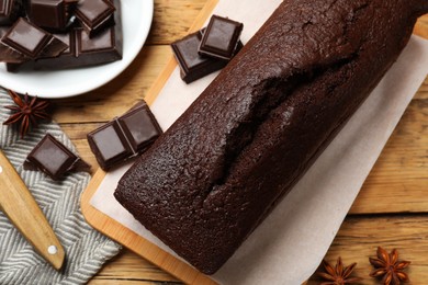 Photo of Tasty chocolate sponge cake and ingredients on wooden table, top view