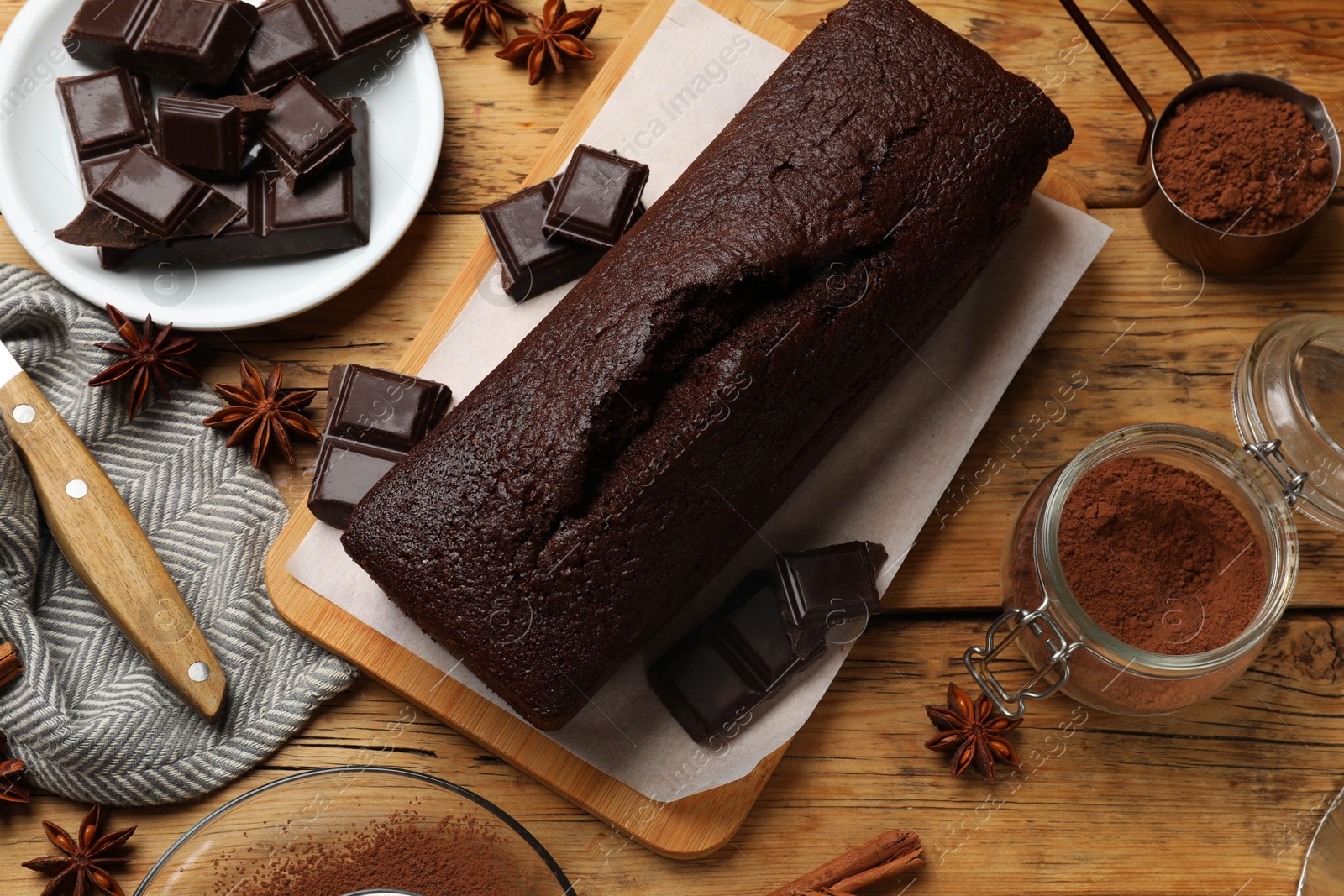 Photo of Tasty chocolate sponge cake and ingredients on wooden table, top view