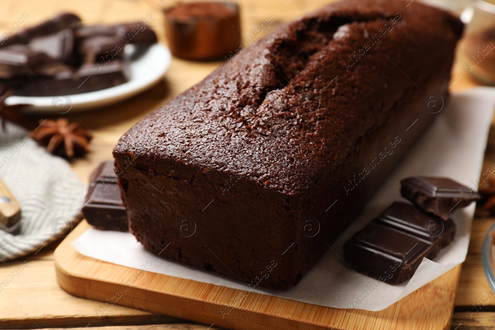 Photo of Tasty sponge cake and pieces of chocolate on wooden table, closeup