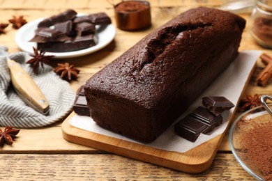 Photo of Tasty sponge cake and pieces of chocolate on wooden table, closeup