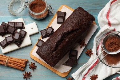 Photo of Tasty chocolate sponge cake and ingredients on light blue wooden table, top view