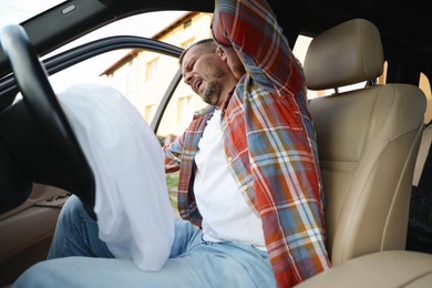 Photo of Injured man near opened airbag in automobile after car accident