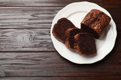 Photo of Delicious cut chocolate sponge cake on wooden table, top view. Space for text