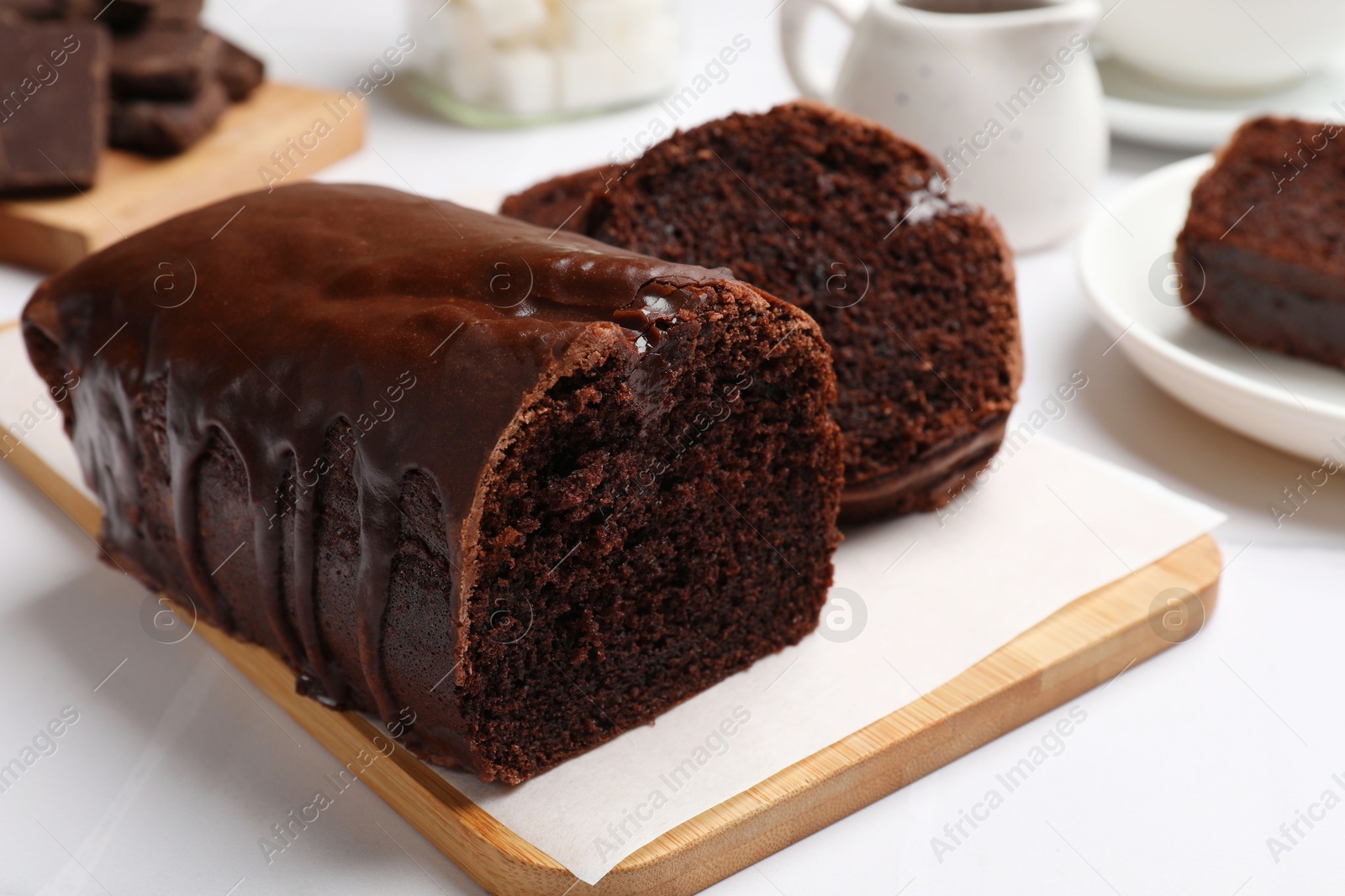 Photo of Delicious chocolate sponge cake on white tiled table, closeup