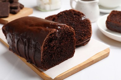 Photo of Delicious chocolate sponge cake on white tiled table, closeup