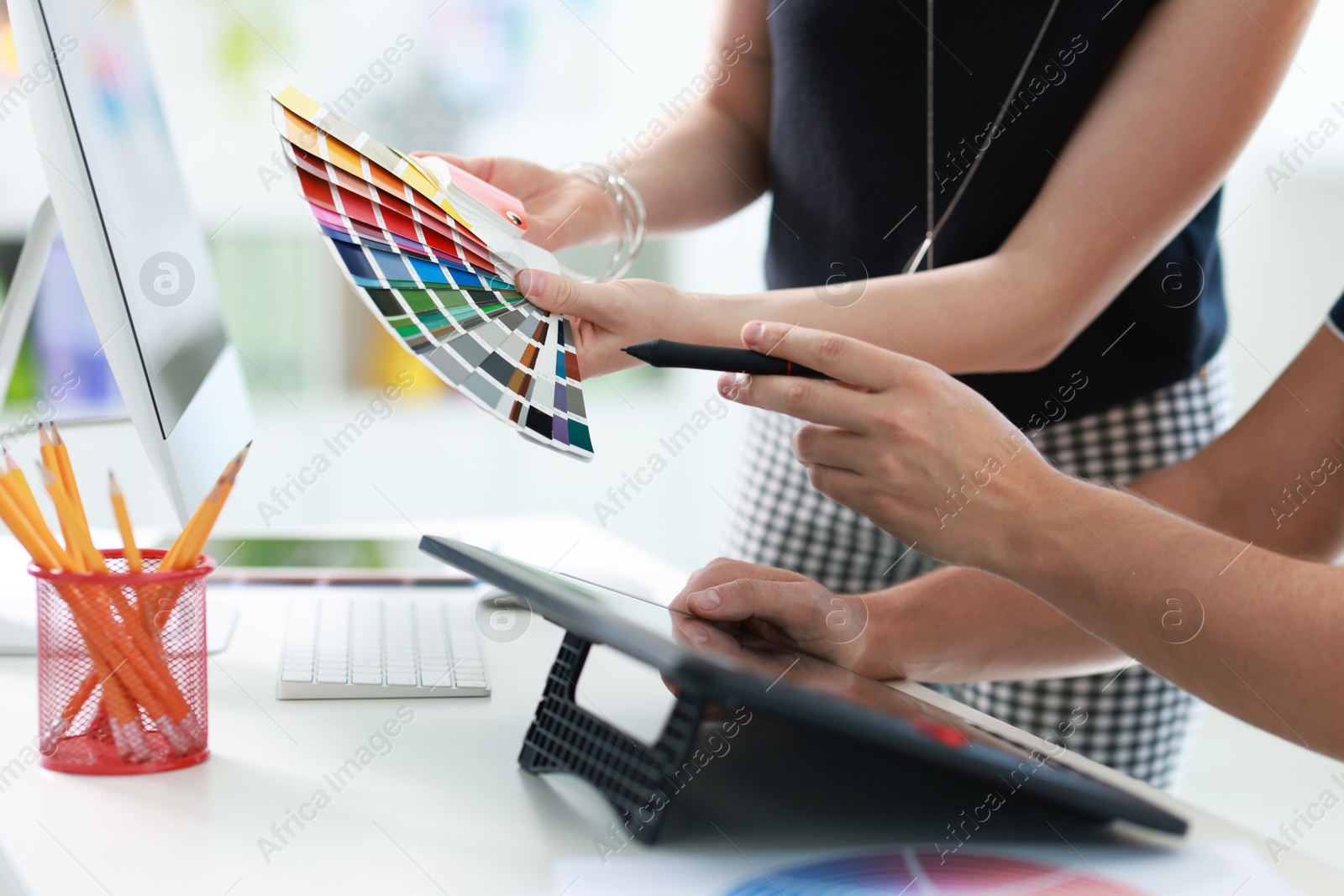 Photo of Designers with color samples and tablet working together in office, closeup