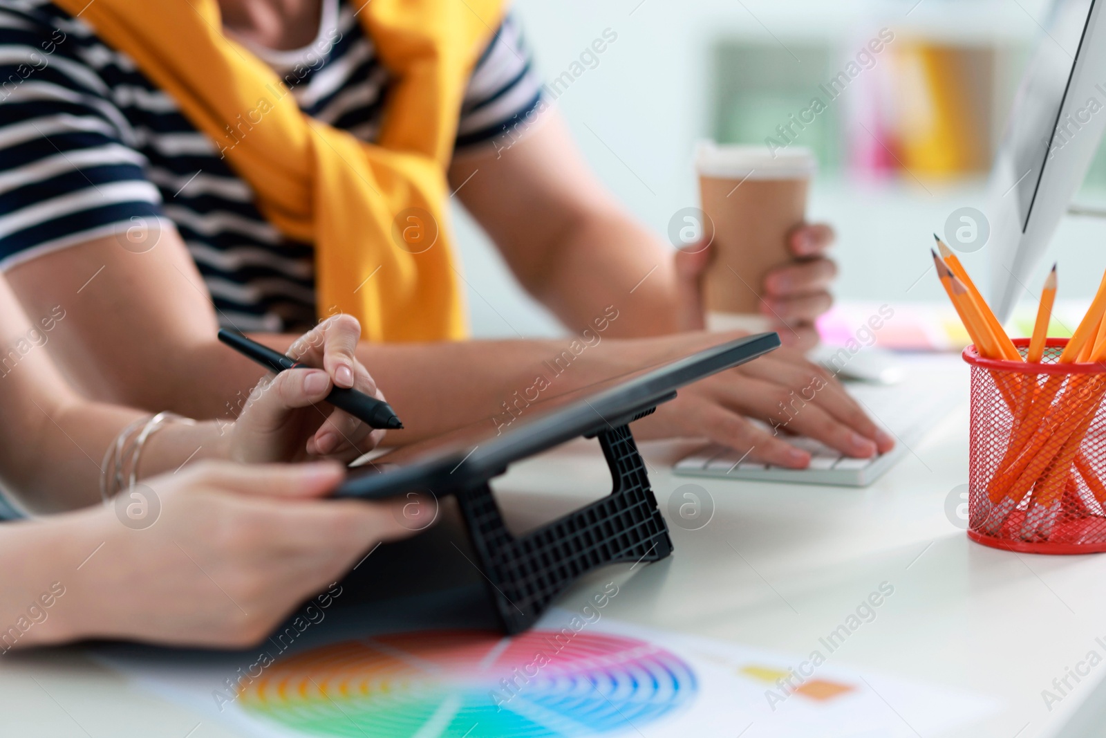 Photo of Designers with tablet working together at table in office, closeup