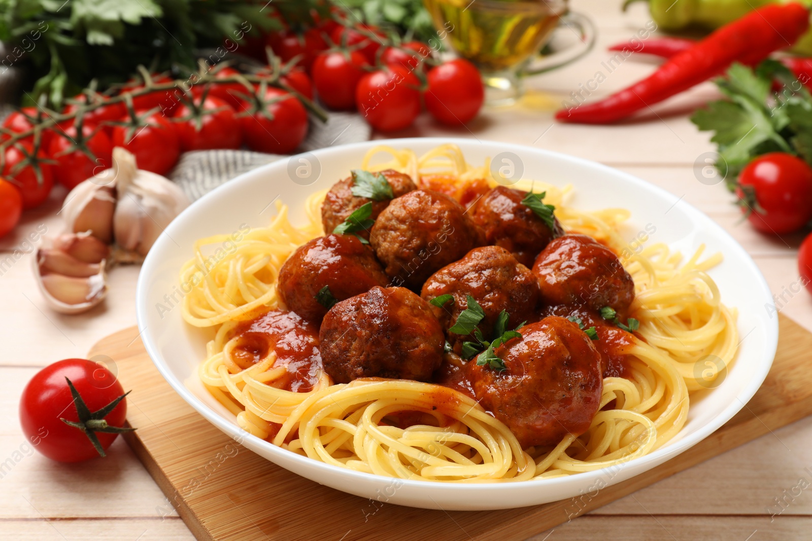 Photo of Delicious pasta with meatballs and ingredients on white wooden table, closeup